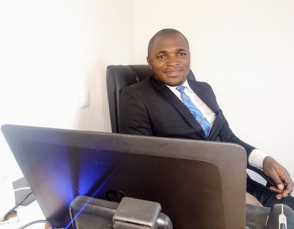 Njofie Wilson in office sitting sideways scaled e1659017715794